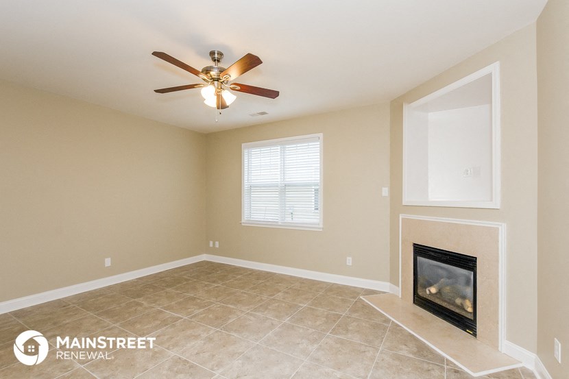 a living room with a fireplace and a ceiling fan