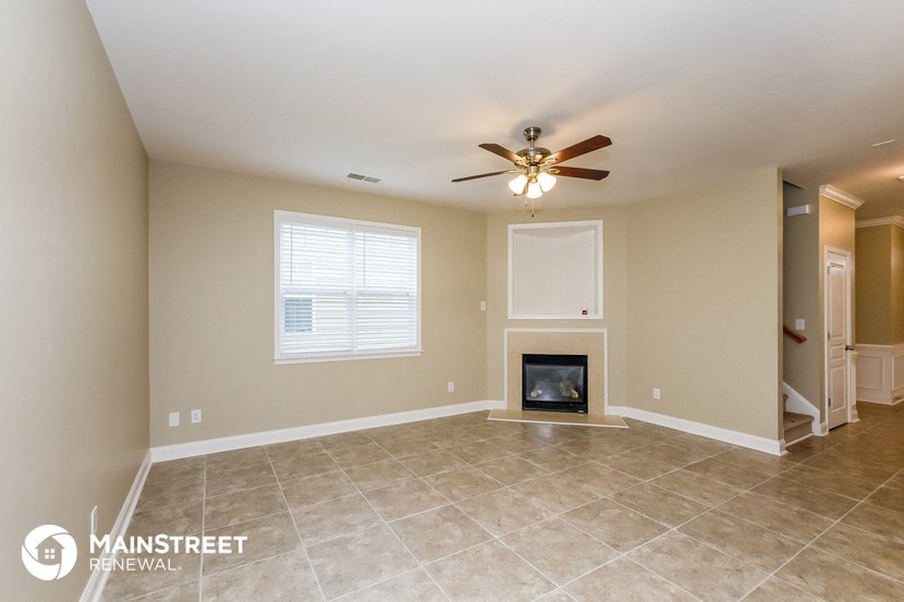 the living room with fireplace and tile flooring and a ceiling fan