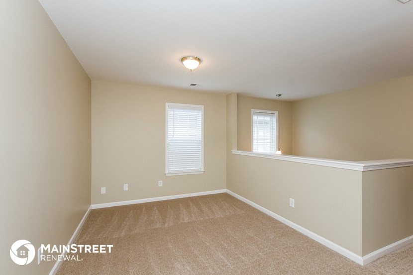 the upstairs bedroom has a large window and carpeted floor