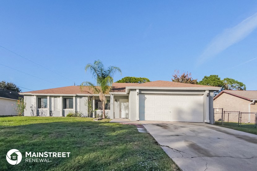 a home with a garage and a palm tree in front of it
