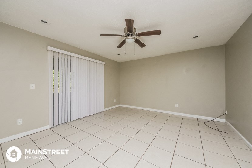 an empty living room with a ceiling fan