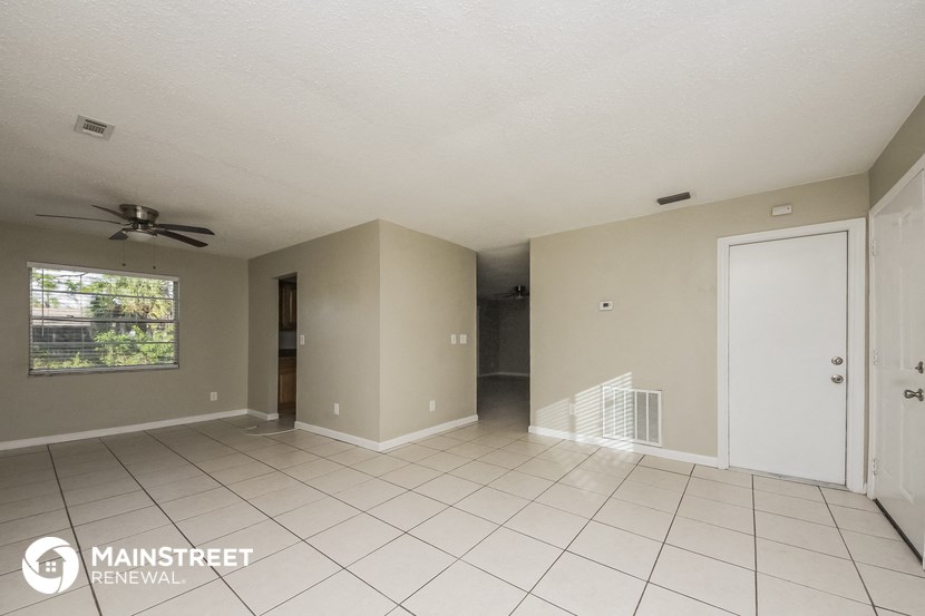 an empty living room with a white tile floor and a ceiling fan