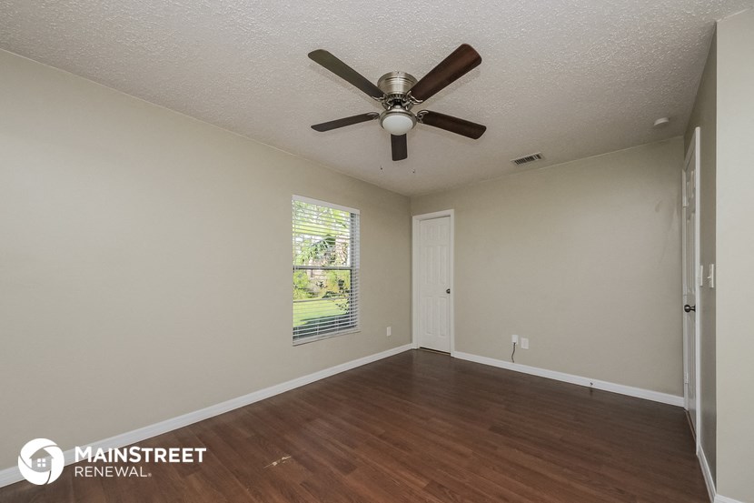 the spacious living room with ceiling fan and wood flooring