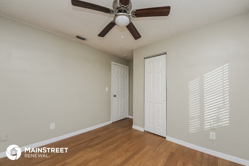 the spacious living room of this manufactured home has a ceiling fan and wood flooring