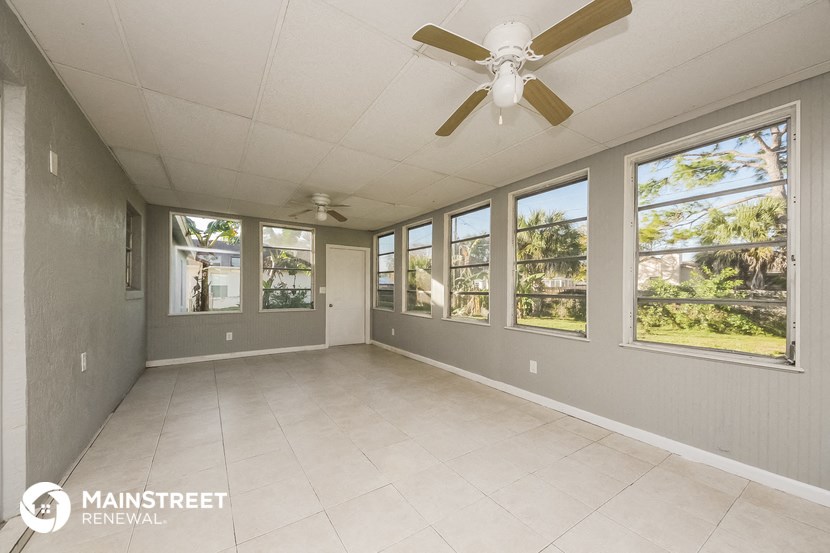 an empty living room with a ceiling fan and windows