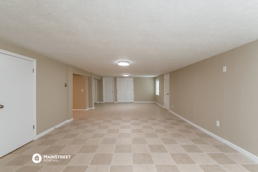 a spacious living room with beige walls and a tiled floor