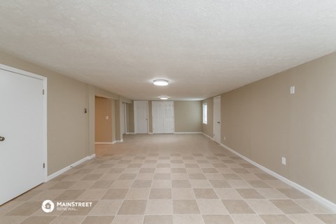 a spacious living room with beige walls and a tiled floor