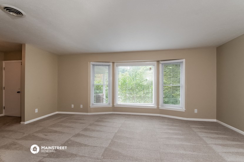 the living room of an empty house with three windows