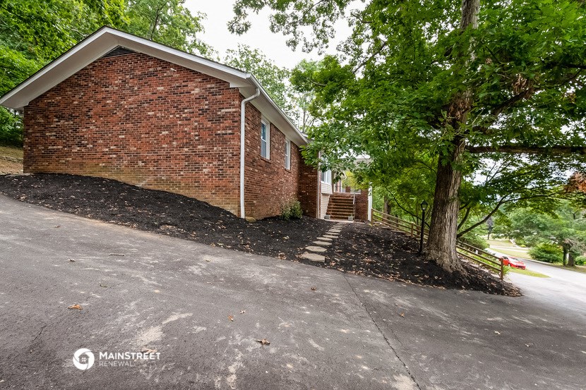 the front of a brick house with a tree on the side