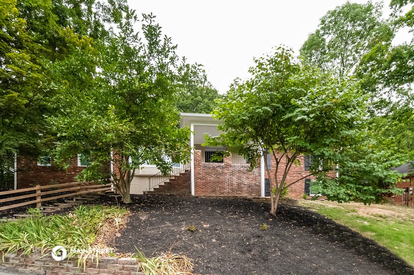 an empty yard with trees and a brick house