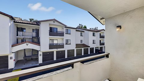 A row of white apartment buildings with balconies and doors.