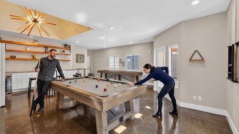 Two people playing pool in a well-lit room.
