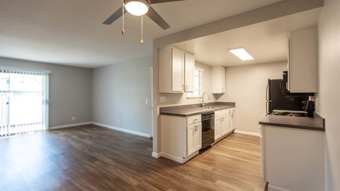 A kitchen with white cabinets and a black fridge.