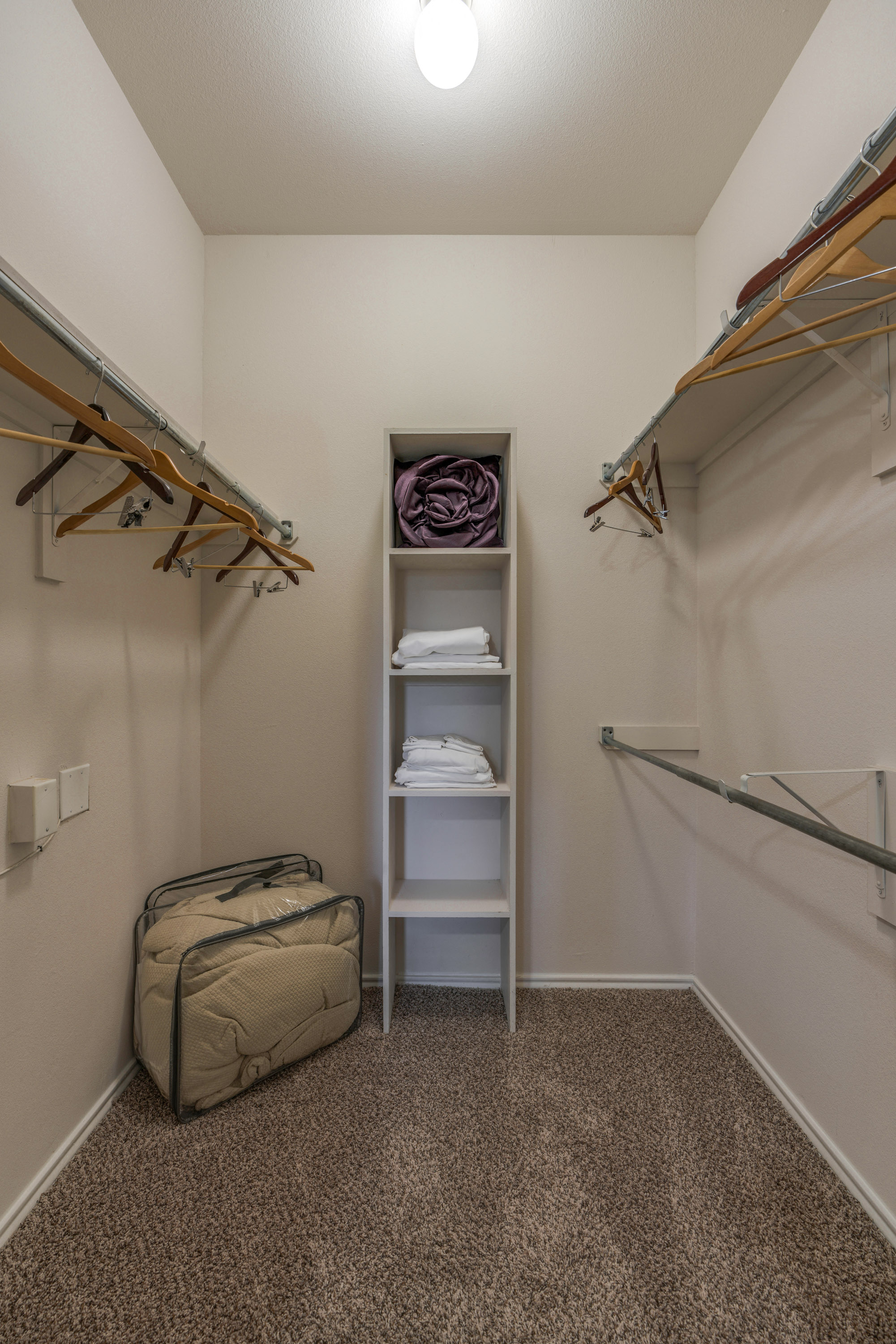 a walk in closet with a luggage bag and a shelf with folded towels