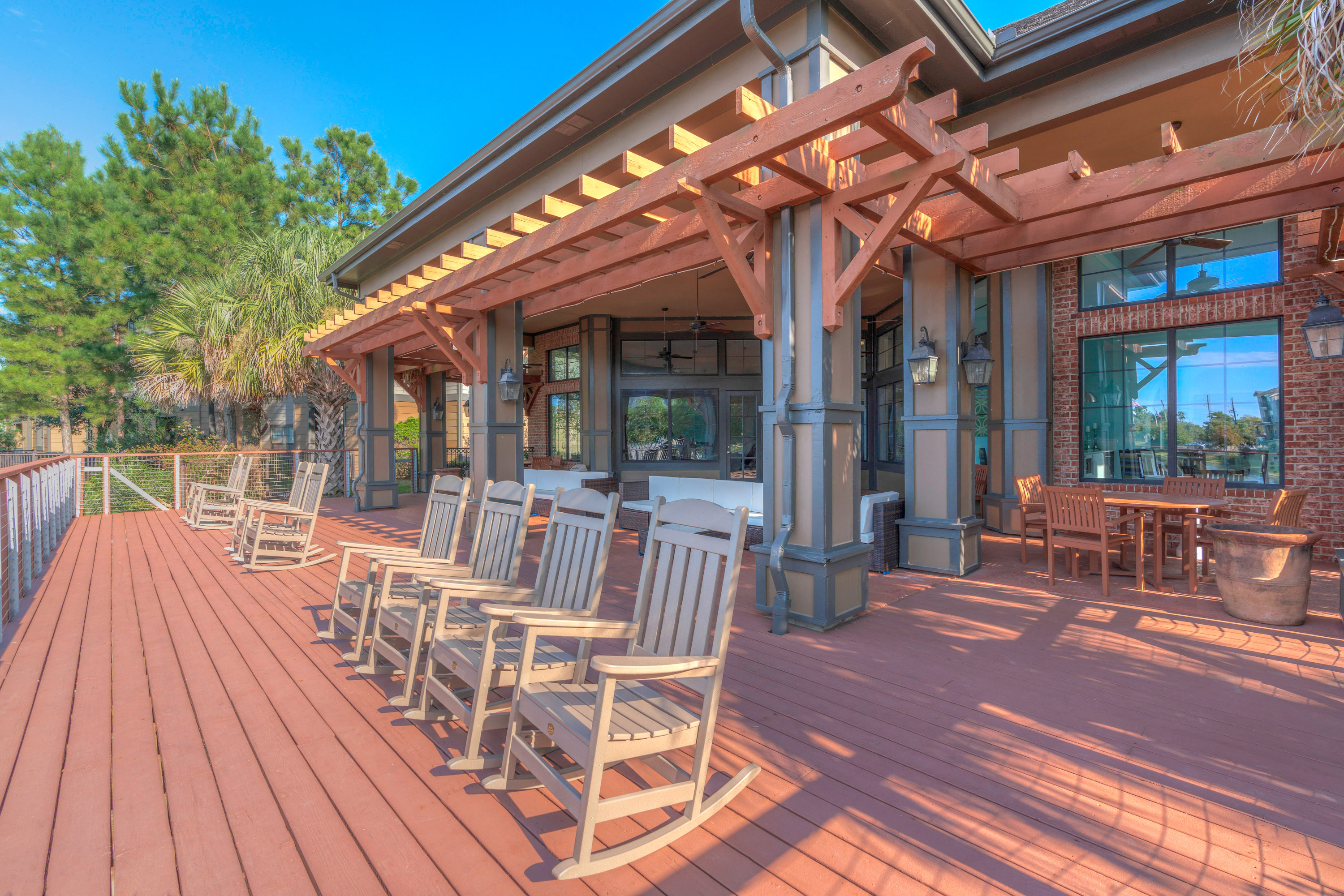 a covered patio with rocking chairs and a house