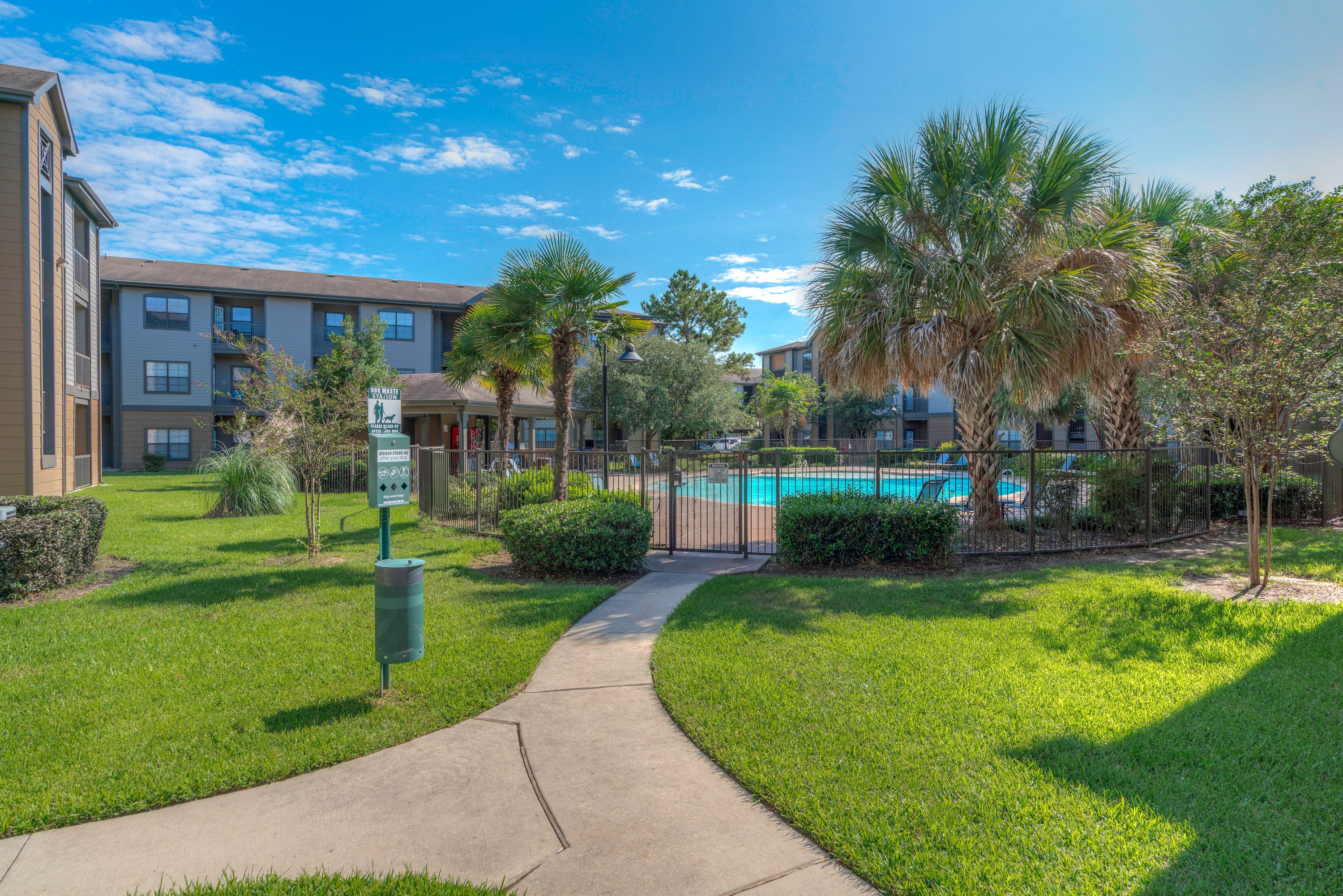 a sidewalk leading to an apartment building with a swimming pool