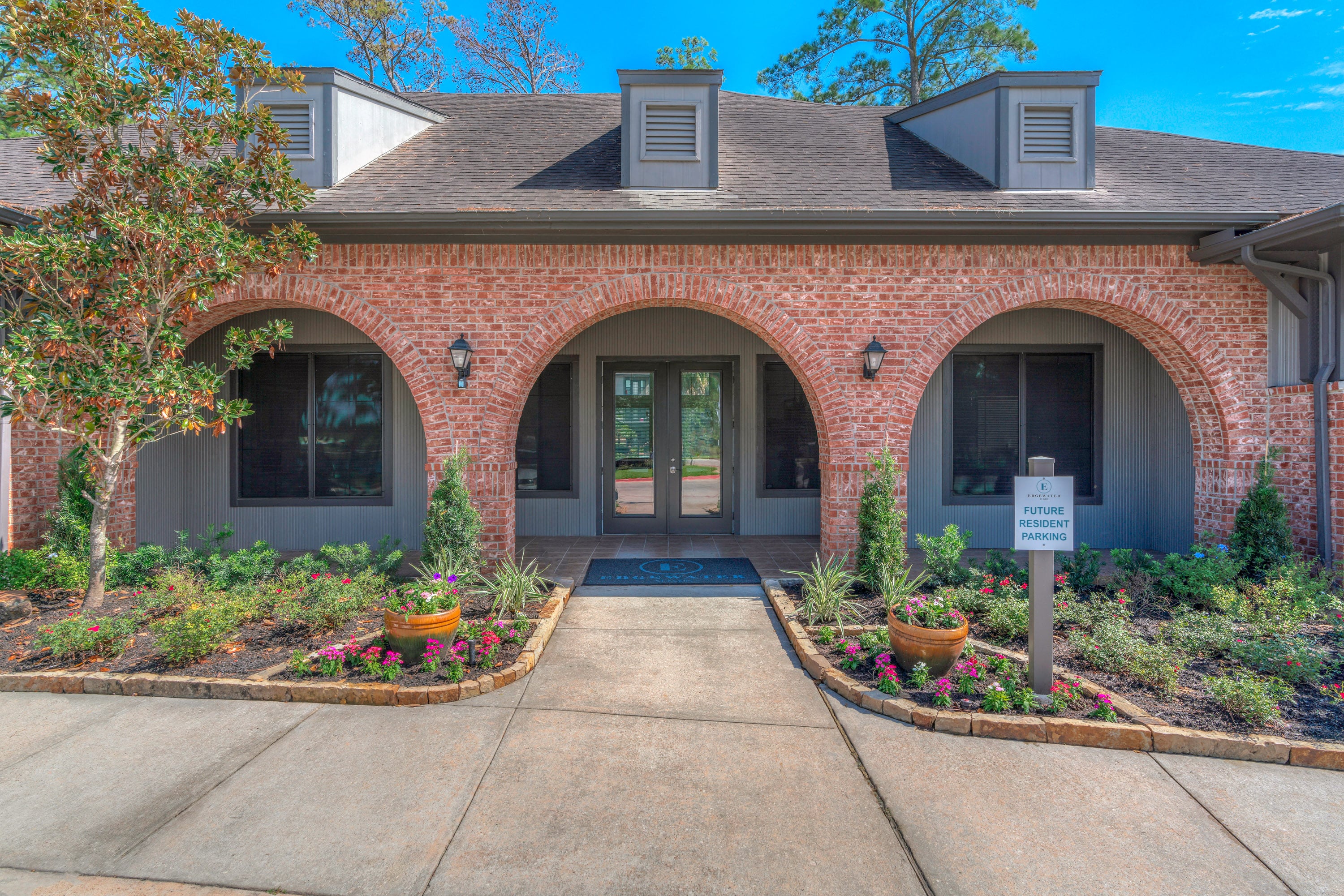 the front entrance of a brick house with a sidewalk and plants