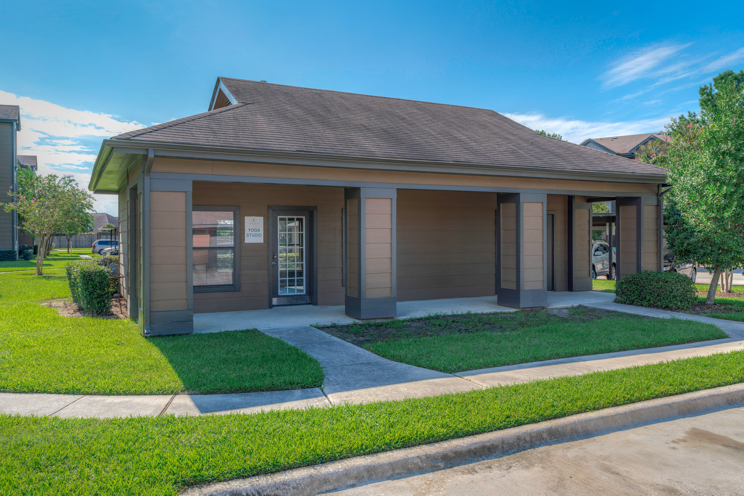 a small brown house with a driveway and grassy lawn