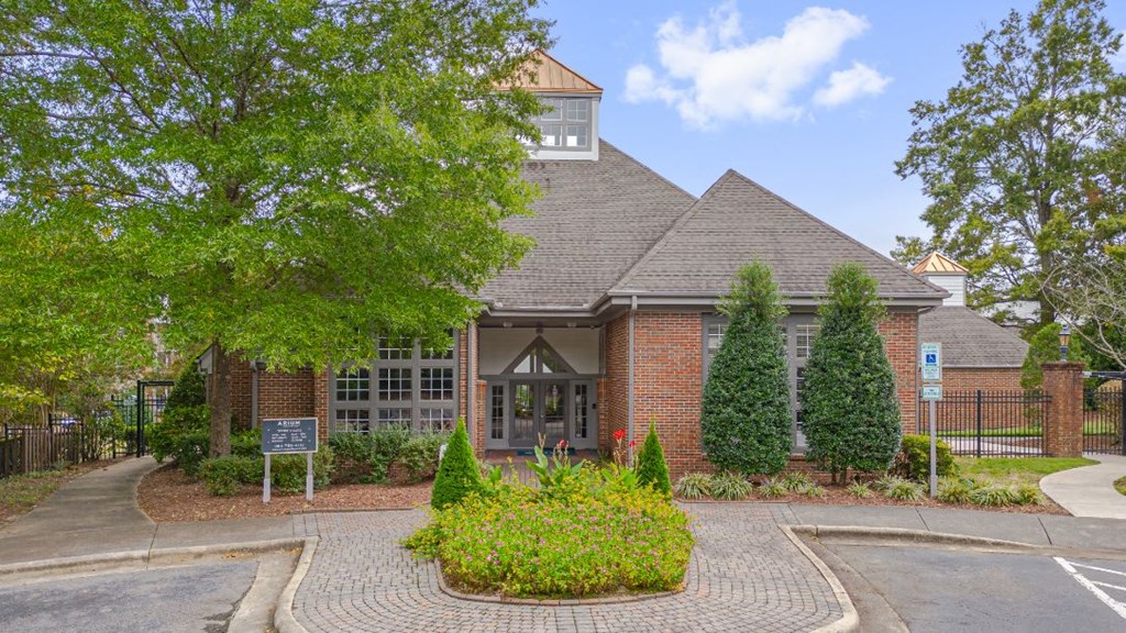 the front entrance of a brick building with trees and bushes