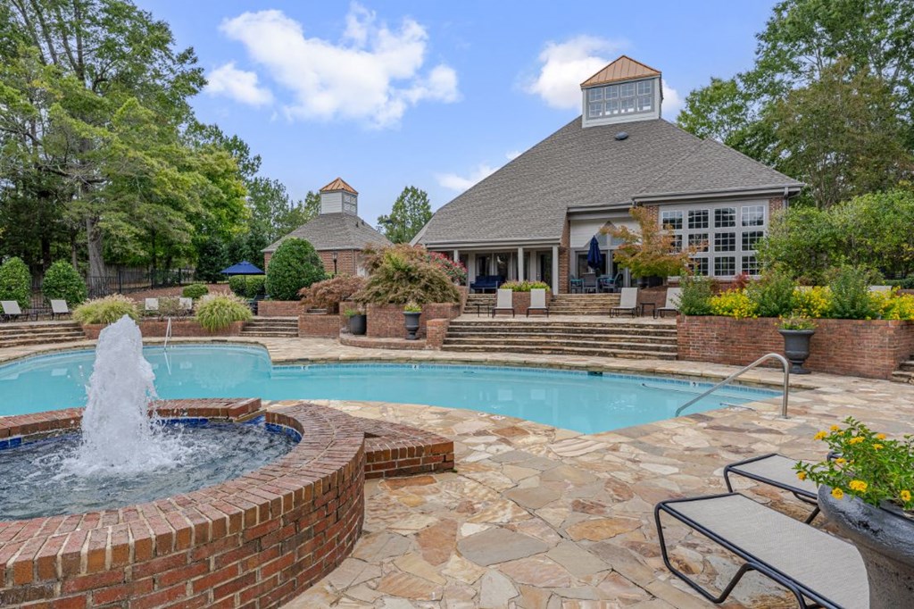 a swimming pool with a fountain in front of a house