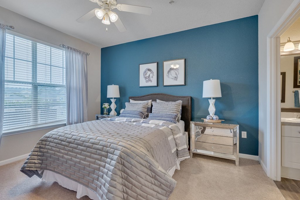 a bedroom with a bed and a blue wall and a ceiling fan