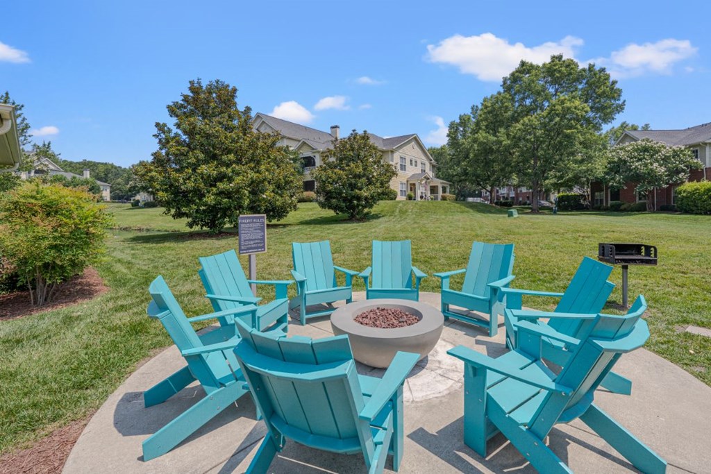 a patio with blue chairs and a fire pit
