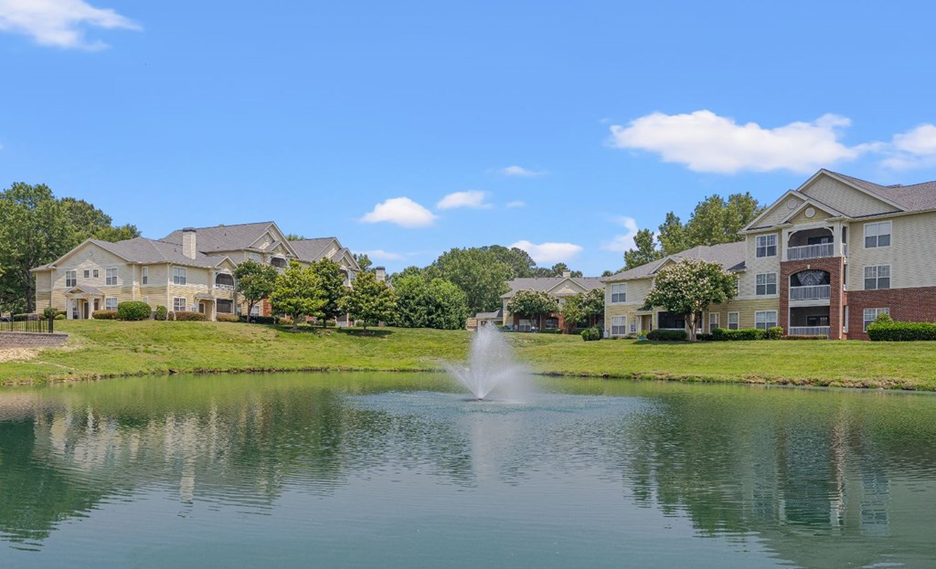 a fountain in the middle of a lake with apartments in the background