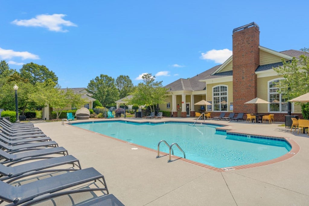 a swimming pool with chairs around it in front of a building