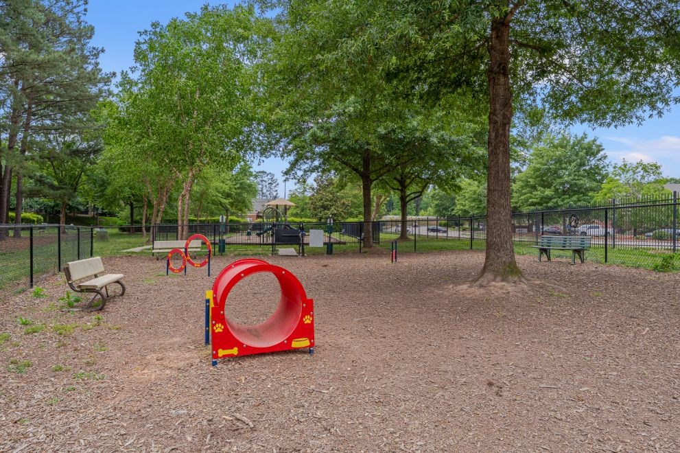 a playground with a red and yellow swing set in a park