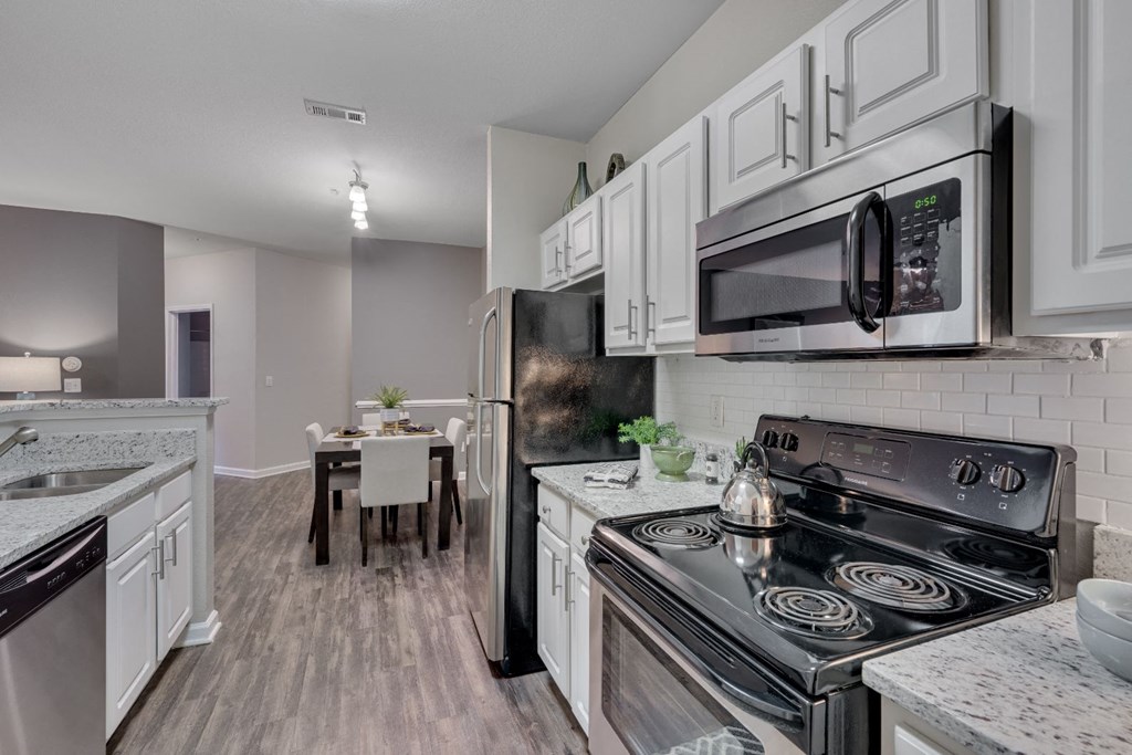 an open kitchen with stainless steel appliances and white cabinets