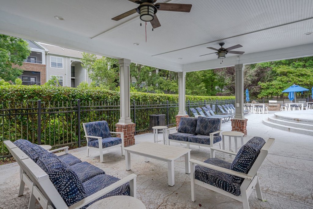 a covered patio with chairs and tables and a pool