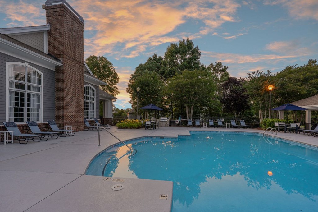 a large pool with chairs and a building with a cloudy sky