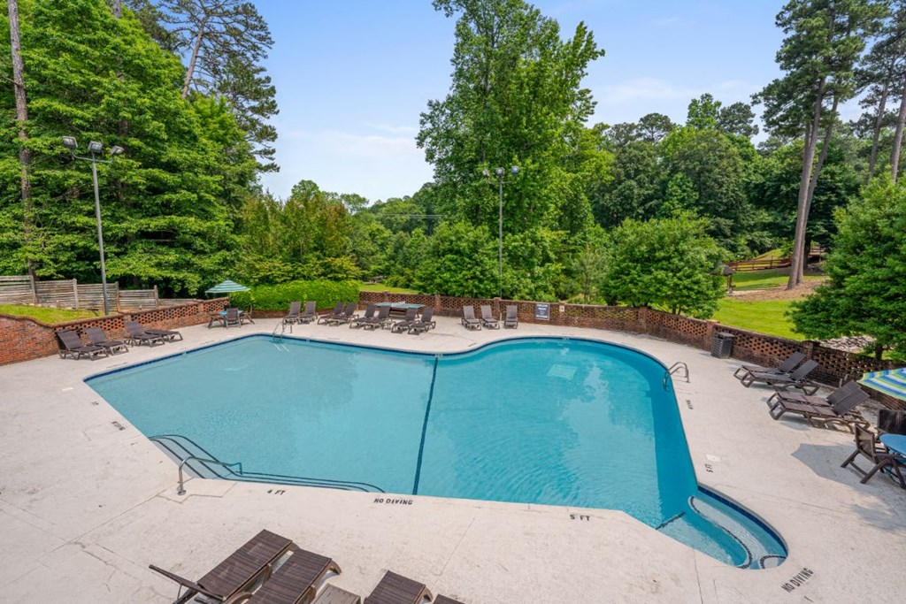a swimming pool with chairs around it and trees