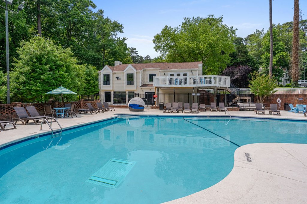 a swimming pool with chairs and a house in the background