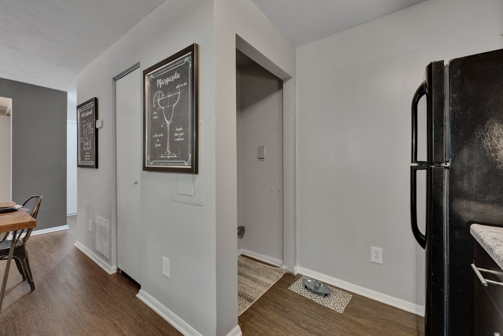 a living room with a refrigerator and a door to a hallway