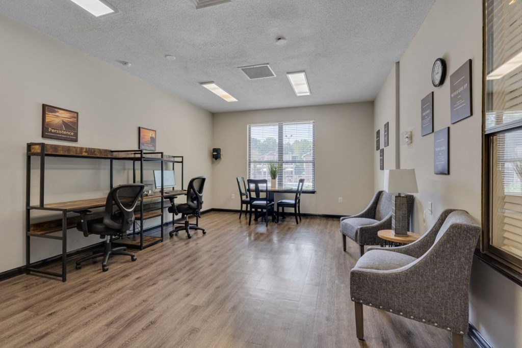 a common room with chairs and a table and a window