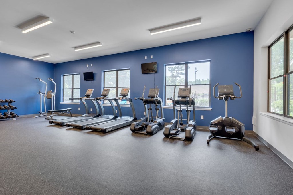 a fitness room with cardio equipment and weights