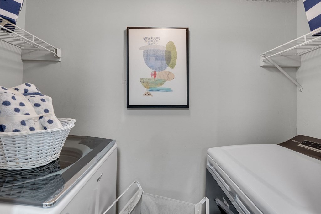 a small laundry room with a washer and dryer and a picture of a