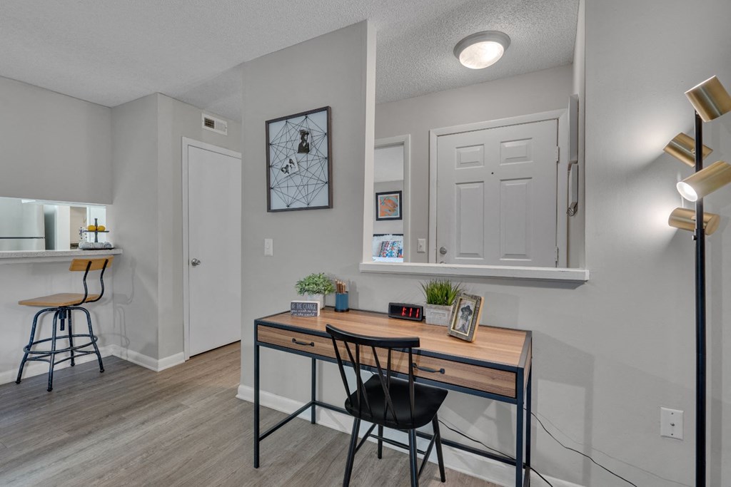 an office area with a desk and chairs and a kitchen with a bar and a