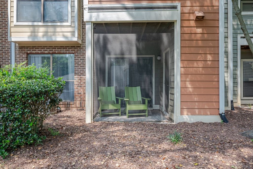 two green chairs in a screened in porch of a house