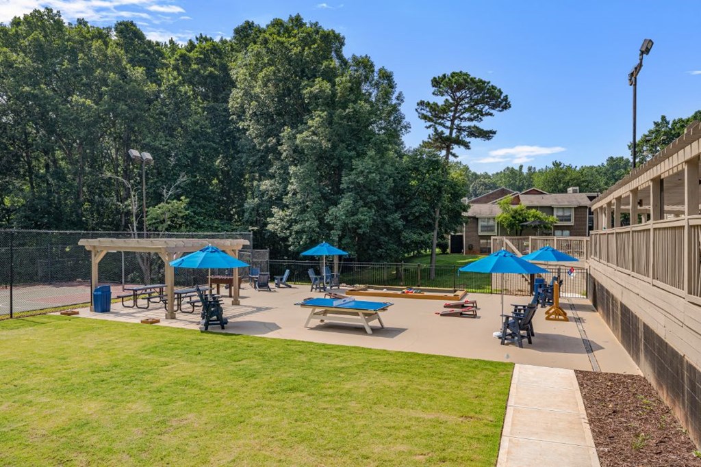 a playground with picnic tables and umbrellas in front of a building
