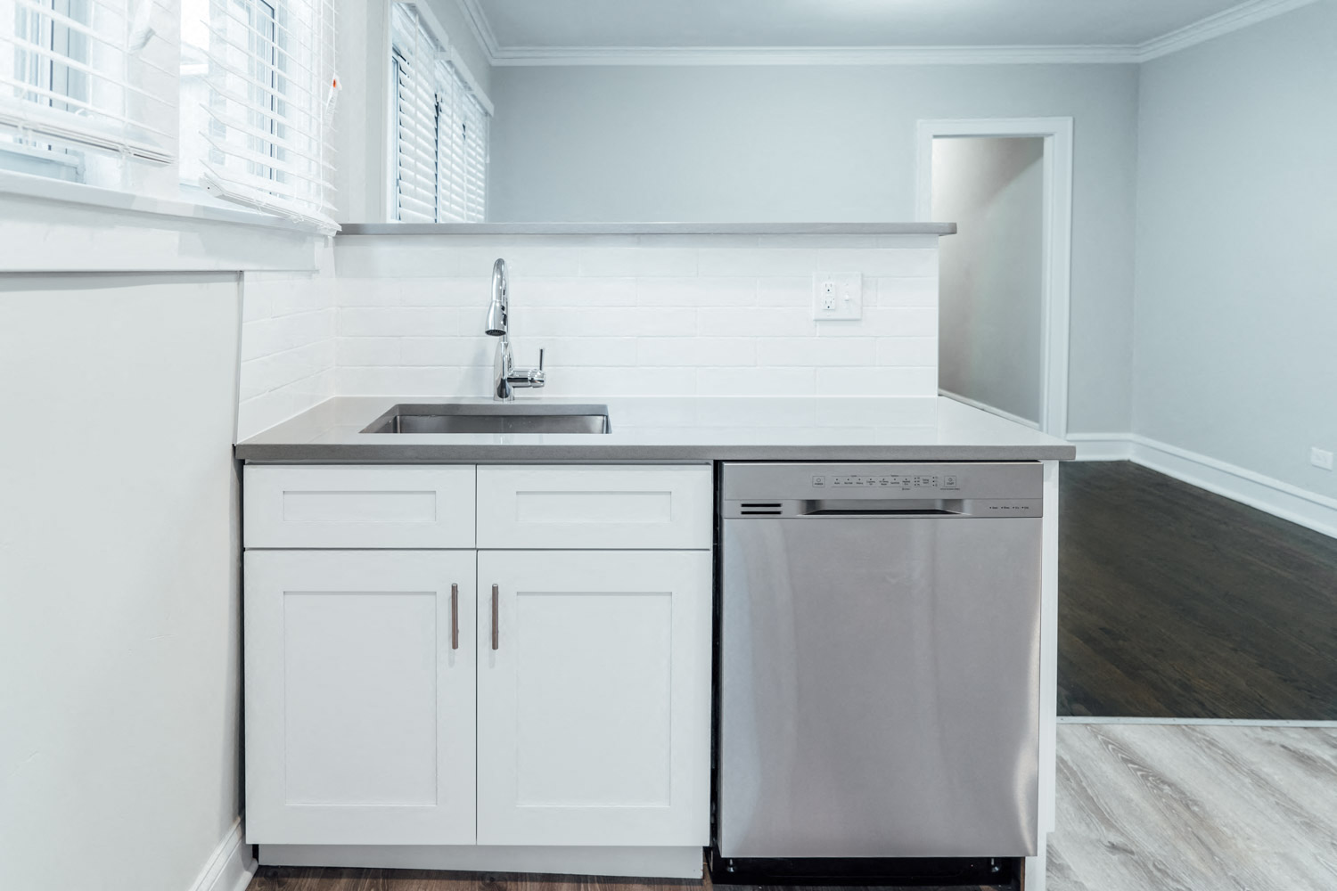 a kitchen with white cabinets and a stainless steel dishwasher