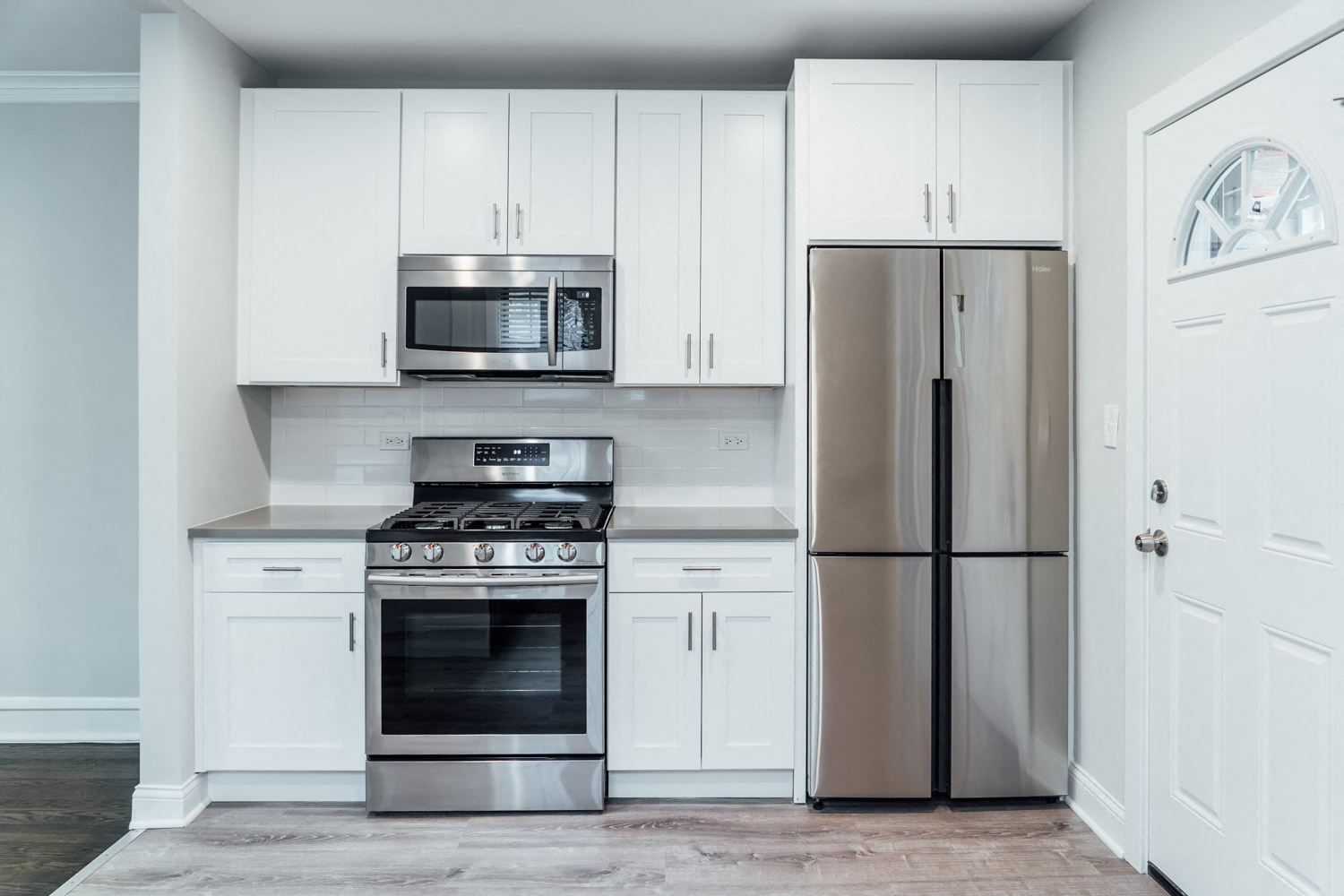 a white kitchen with stainless steel appliances and white cabinets