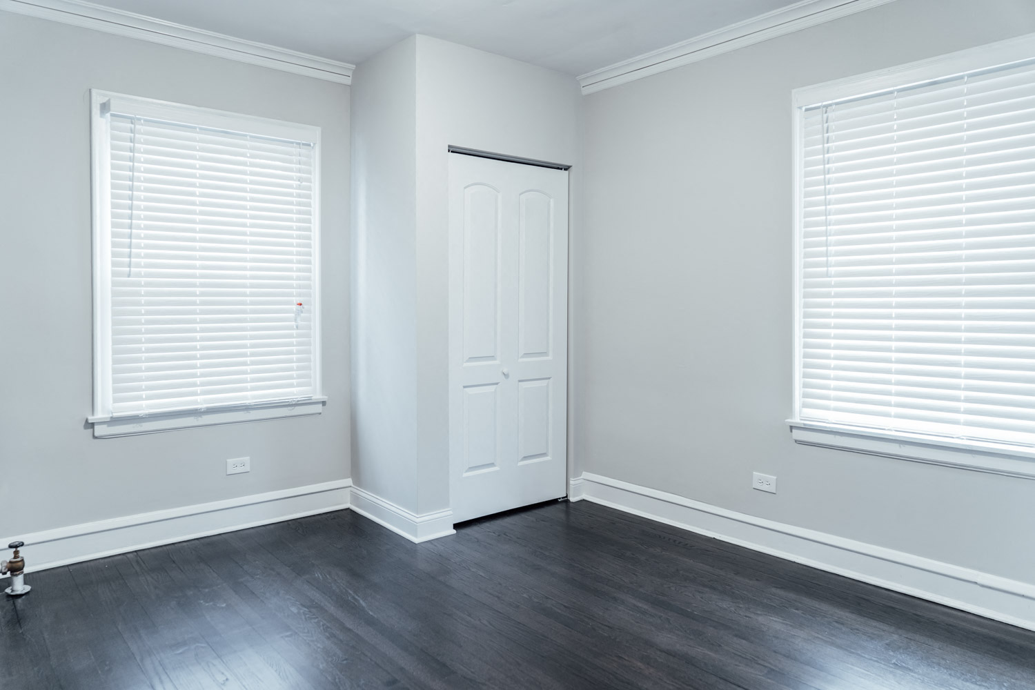 an empty room with a door and two windows