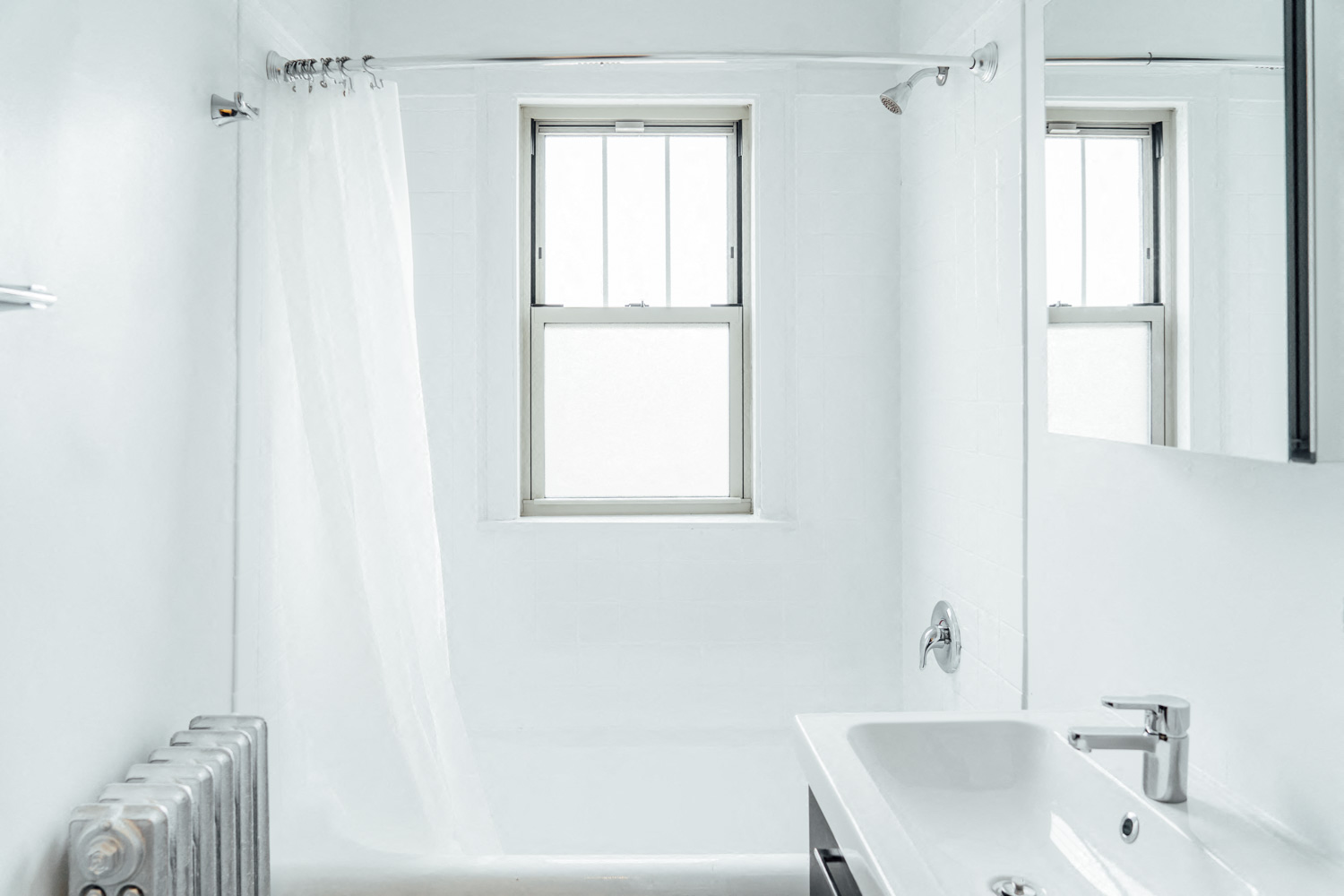 a white bathroom with a tub and a sink and a window