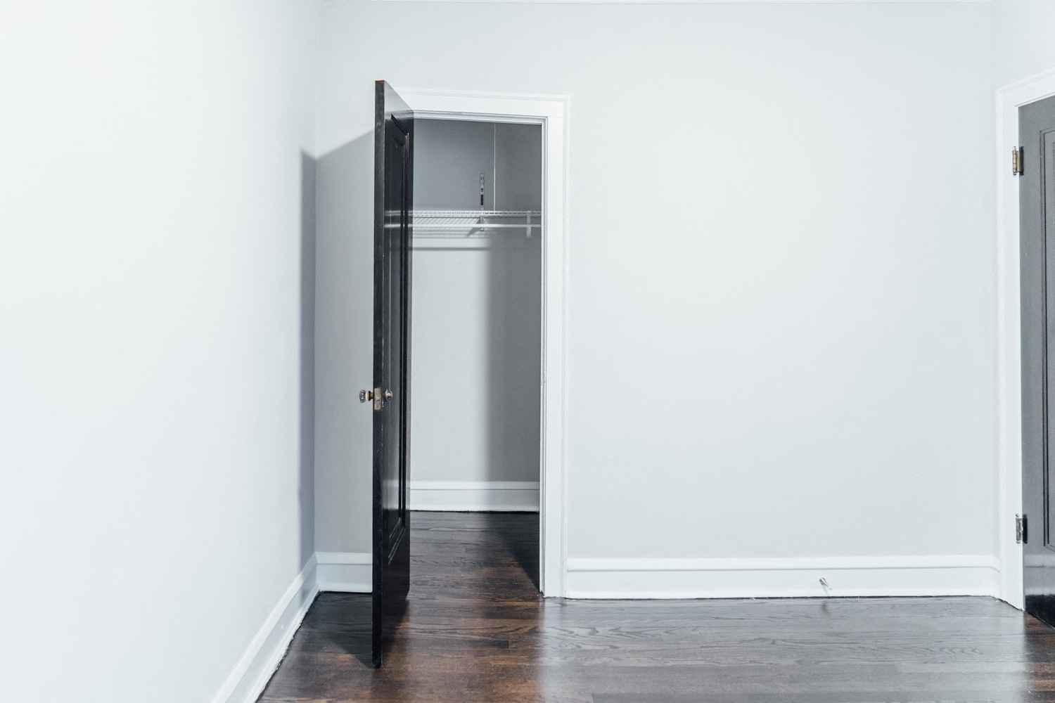 an open door in a white room with a refrigerator