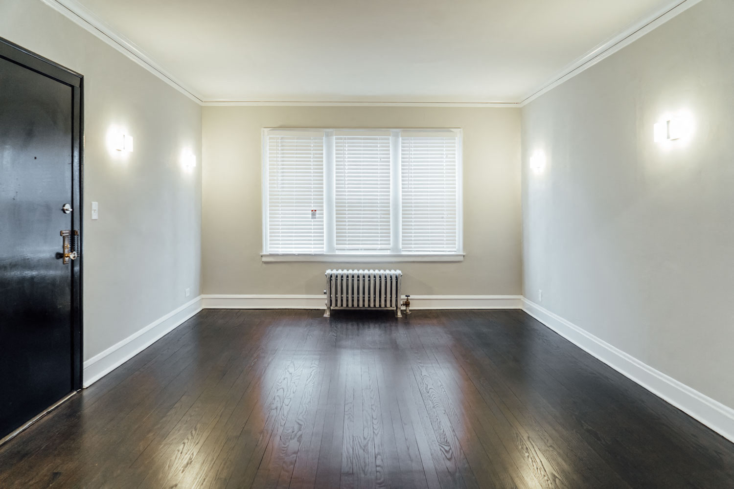 an empty living room with wood floors and a window