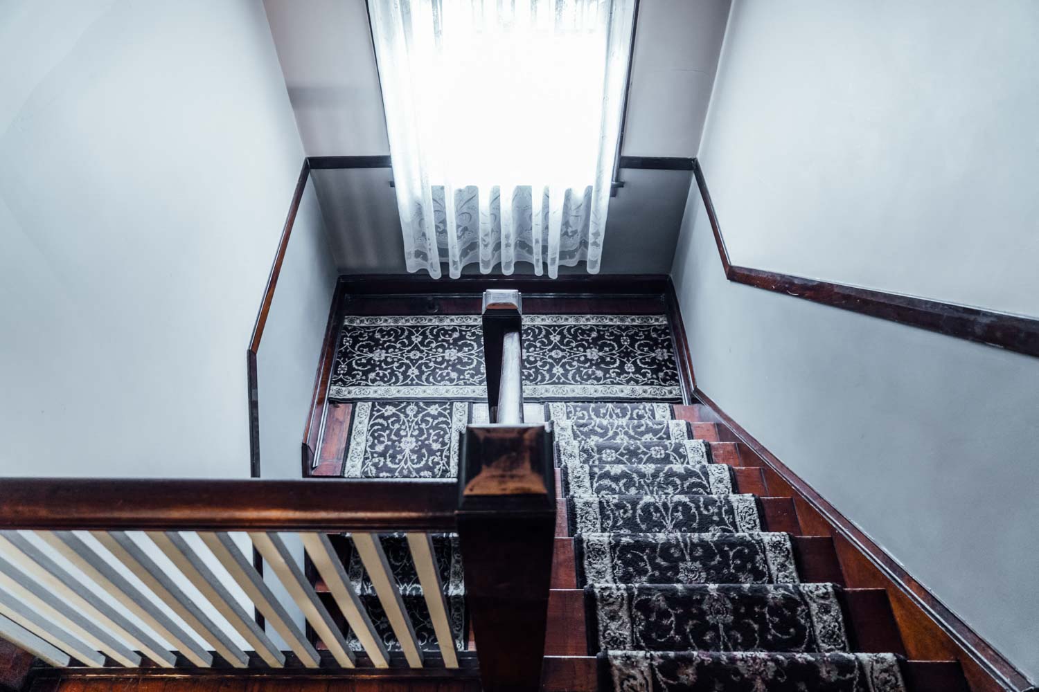 a view down the stairs of a window with a curtain