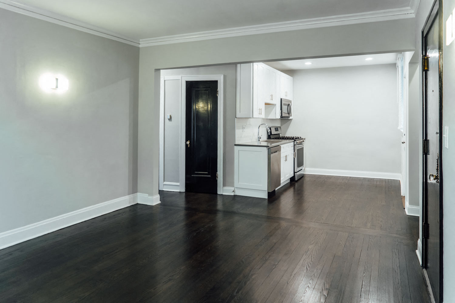 a renovated living room and kitchen with wood floors and white walls
