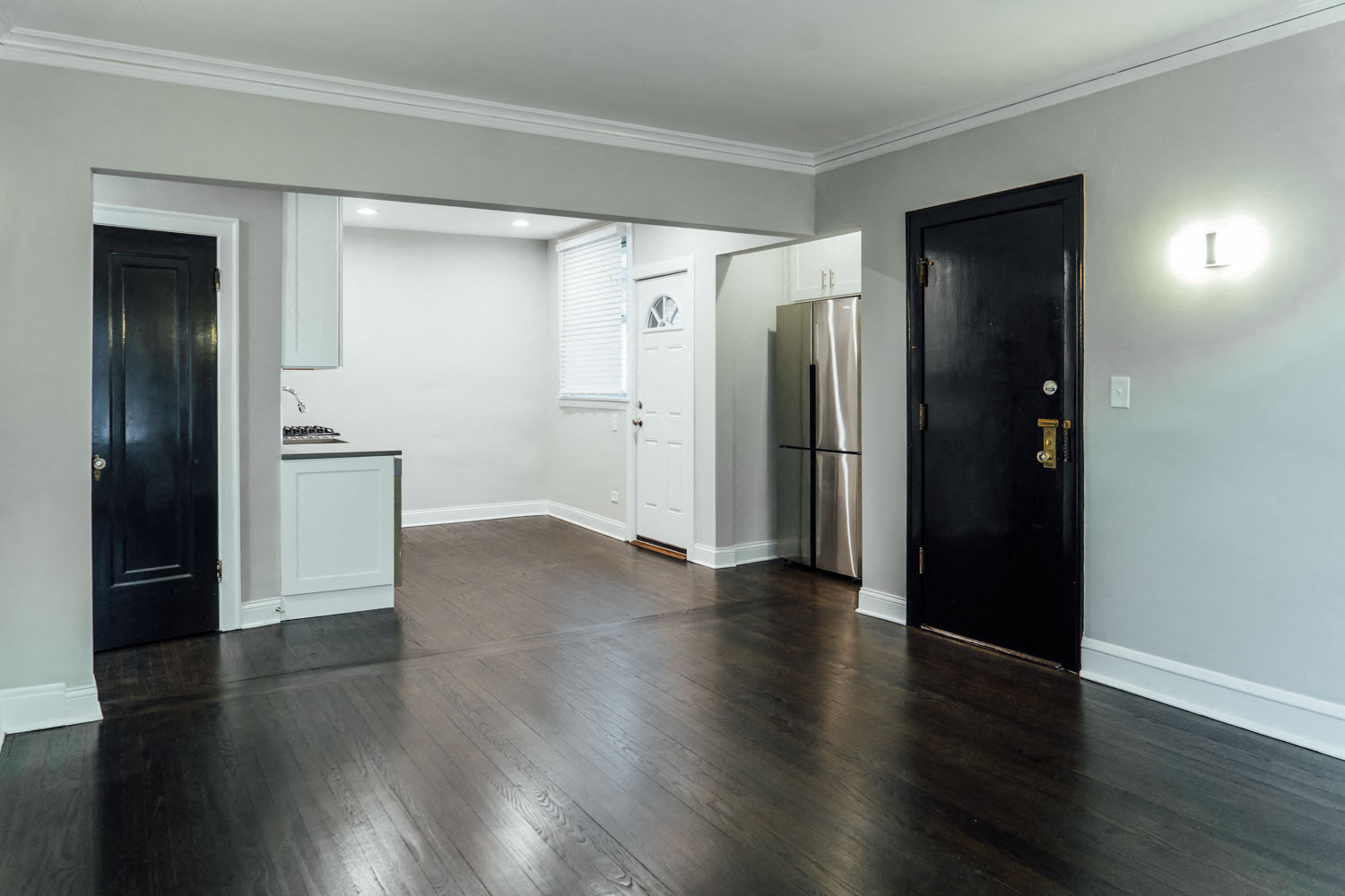 an empty living room with wood floors and a black door
